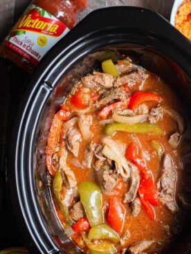 close up of beef strips, onion and bell peppers cooked in slow cooker.