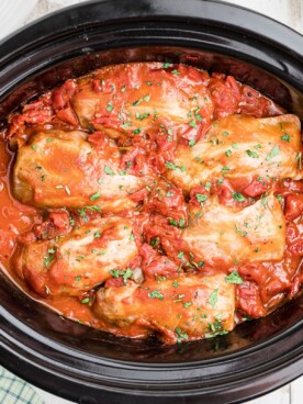 cooked cabbag rolls in red sauce in a slow cooker.