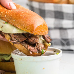french dip sandwich being dipped in au jus.