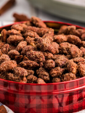 close up of cinnamon almonds in a red and black tin.