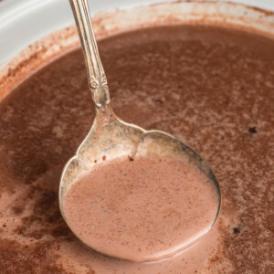 Nutella hot chocolate in a slow cooker and in a metal ladle.